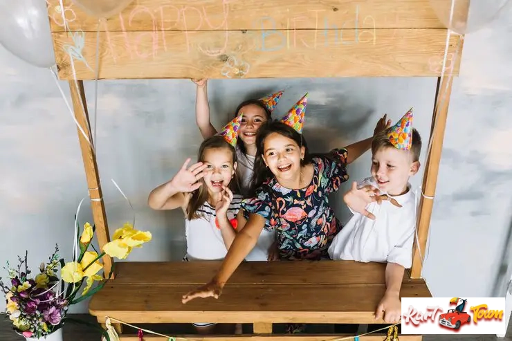 A group of four smiling children, all wearing party hats.