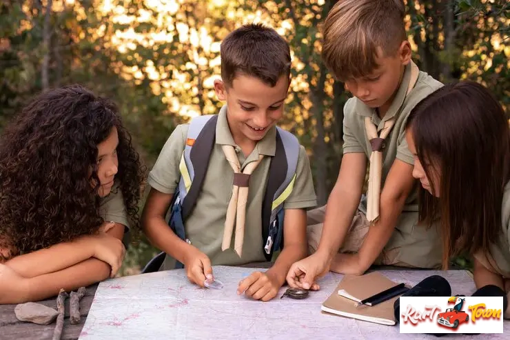 Four young scouts, looking at a map, compass, and binoculars.