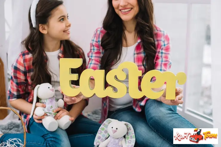 Smiling mom and girl holding a yellow Easter sign with bunnies.