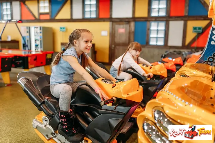 Two girls enjoying a motorcycle racing simulator at an indoor arcade.