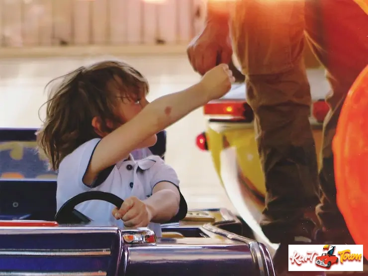 A young student in a go-kart interacting with a field trip supervisor.