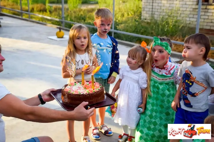 Outdoor birthday party with kids watching a cake with sparklers.