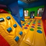 Colorful inflatable play structure with a yellow climbing slope, blue footholds, and rows of colored circles on the floor.