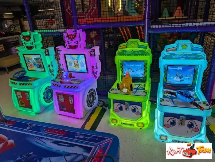 Four colorful arcade game cabinets glow green, purple, lime and blue beside a partially visible air hockey table.