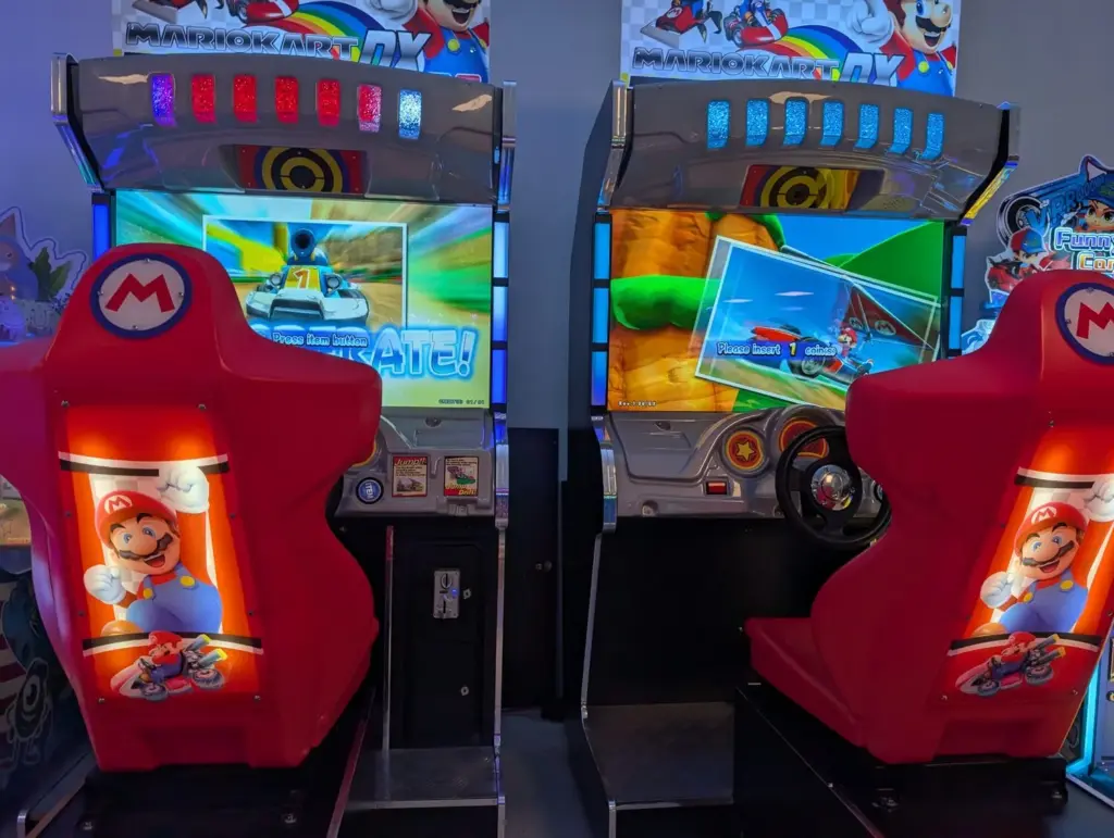 Kids racing side by side on Mario Kart arcade machines in the bright arcade at Kart Town