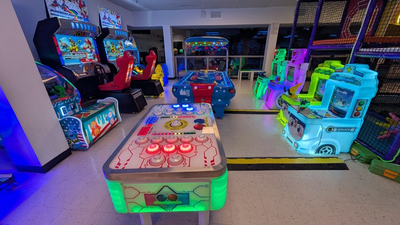 Wide view of the brightly lit arcade floor full of games at Kart Town