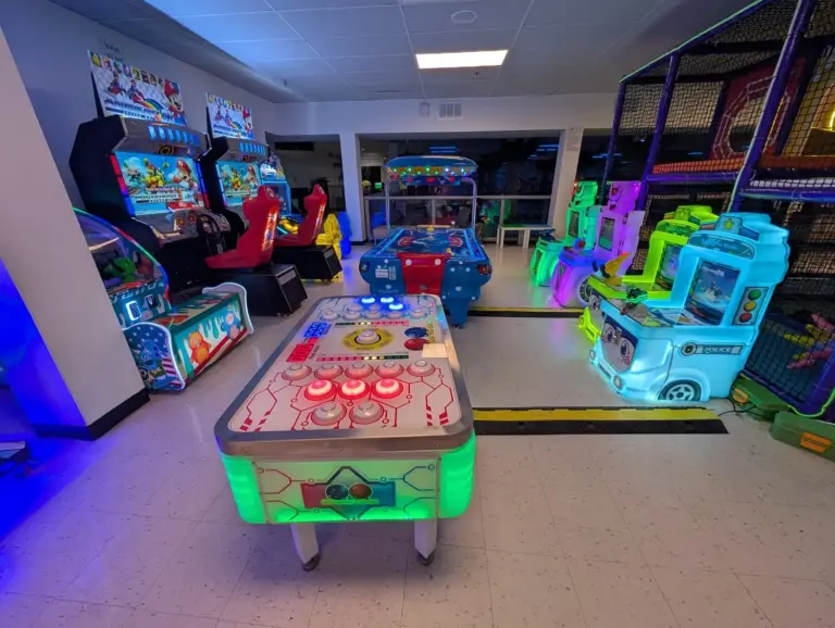 Wide view of the brightly lit arcade floor full of games at Kart Town