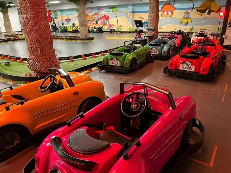 Children riding the classic cars past the palm-tree track