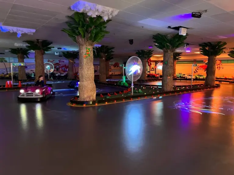 Pink classic car driving around the palm-tree indoor track under sunset lighting