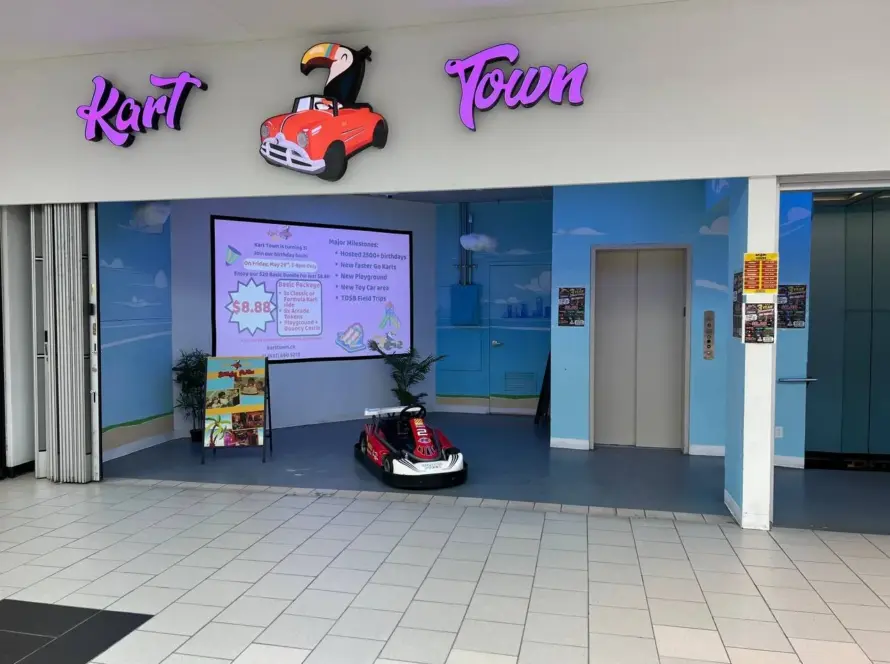 Kart Town storefront entrance with toucan-and-red-car sign, party sign board and welcome kart