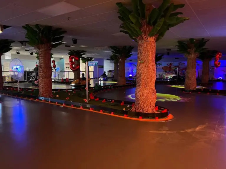 Indoor go-kart track with palm trees and 3rd anniversary balloon decorations