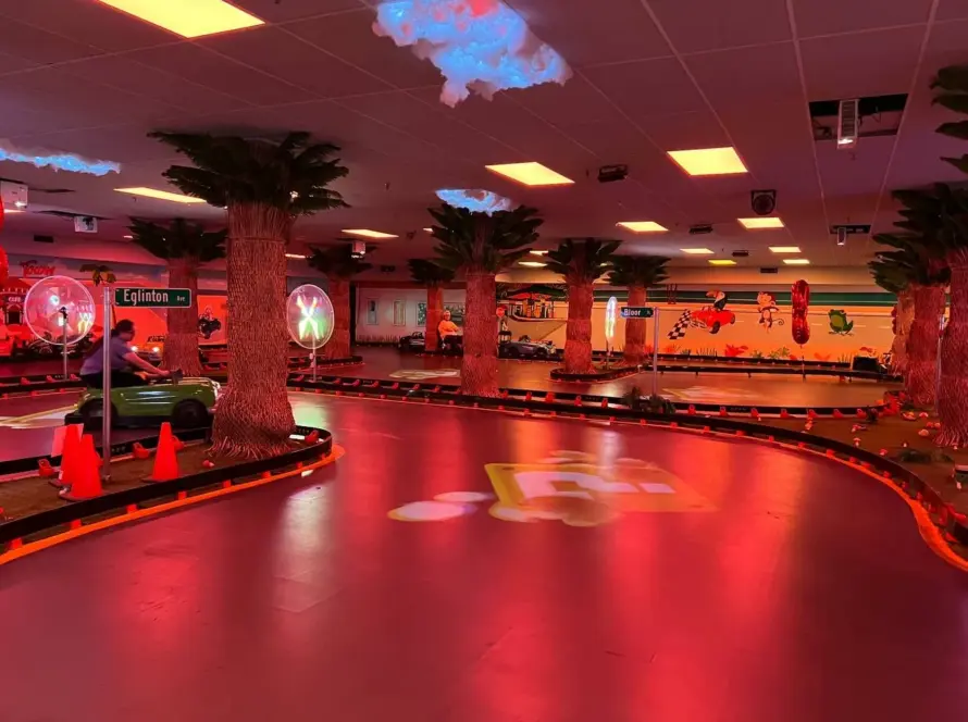 Sweeping curve of the Kart Town track lit in red with palm trees and a green kart passing