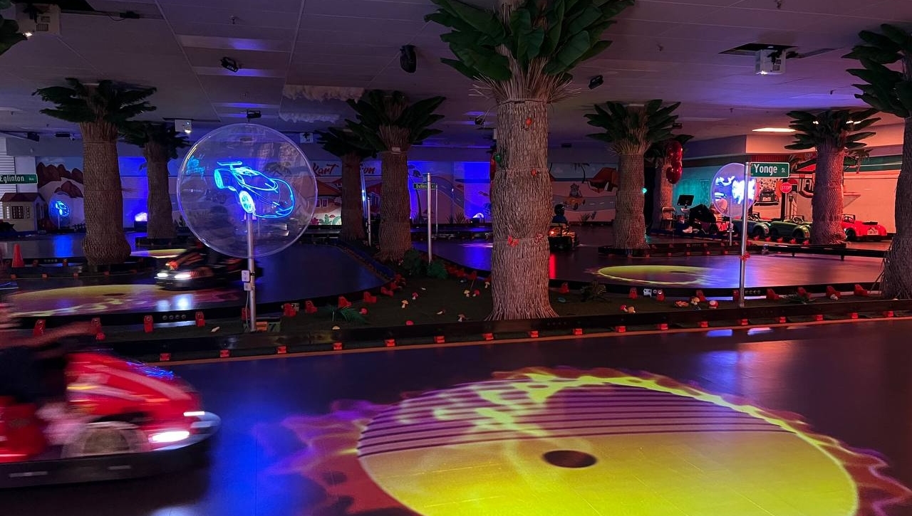 Kart Town track at night with UV lighting, blue race car projection and glowing yellow effects