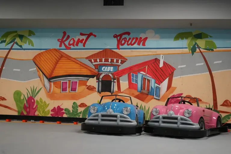 Pink and blue go-karts beside the bright Kart Town beach diner mural