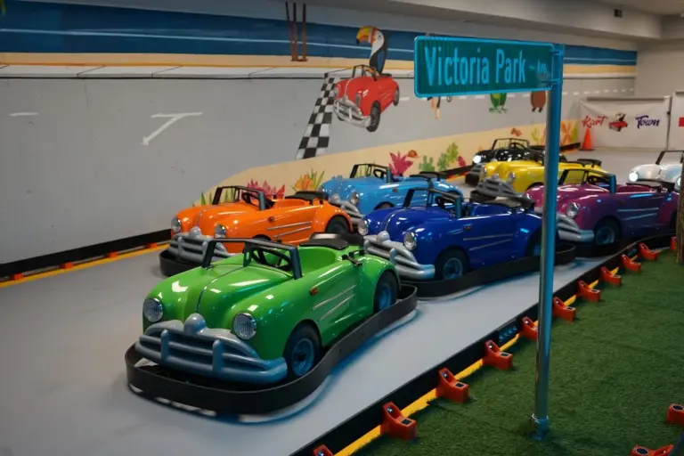 Row of colourful go-karts lined up under the Victoria Park street sign at Kart Town