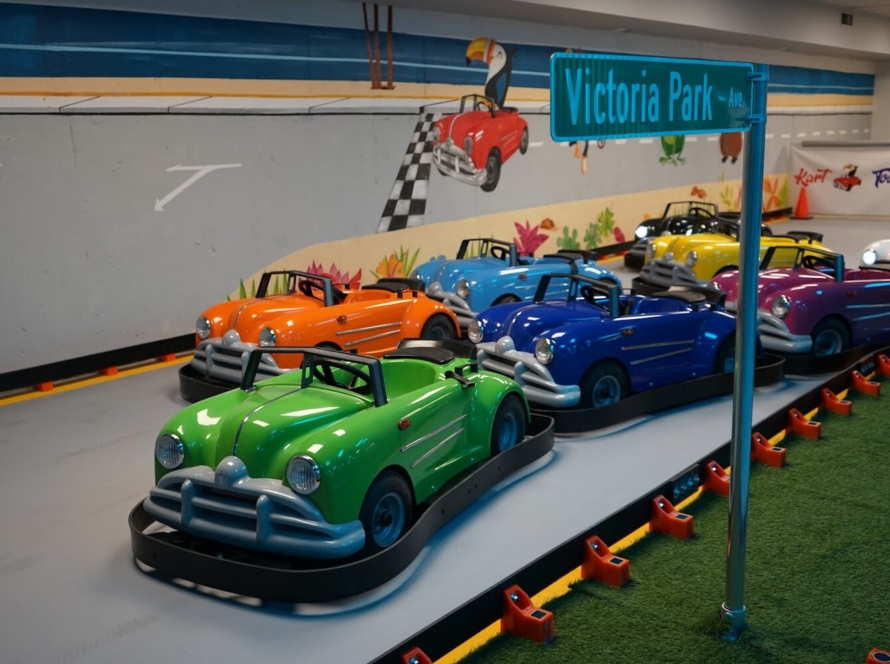 Row of colourful go-karts lined up under the Victoria Park street sign at Kart Town