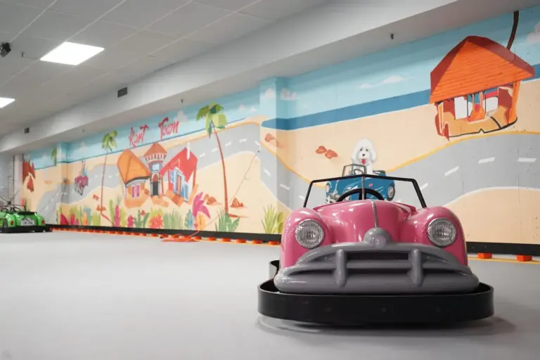 Pink classic-style go-kart facing the camera on the bright indoor track