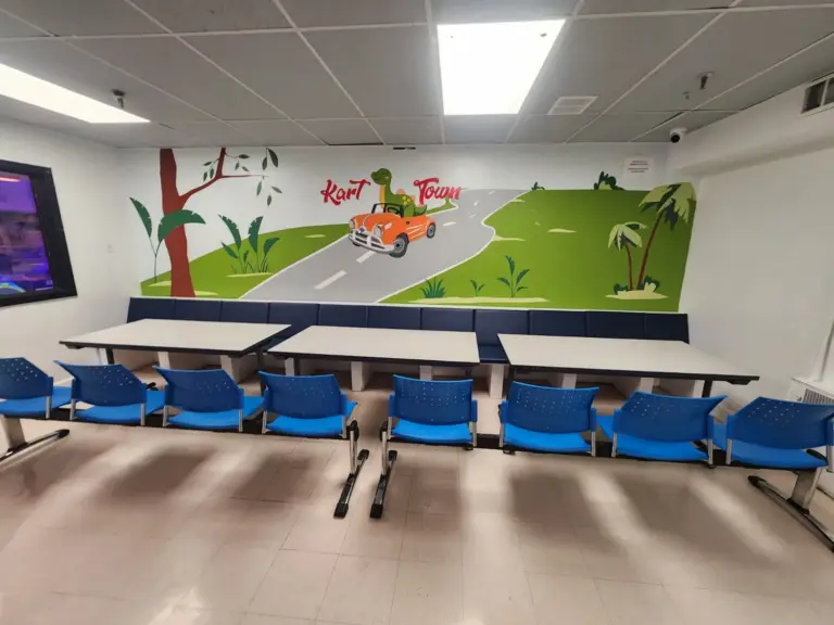 Dino-themed birthday party room with green hills and dinosaur car mural at Kart Town