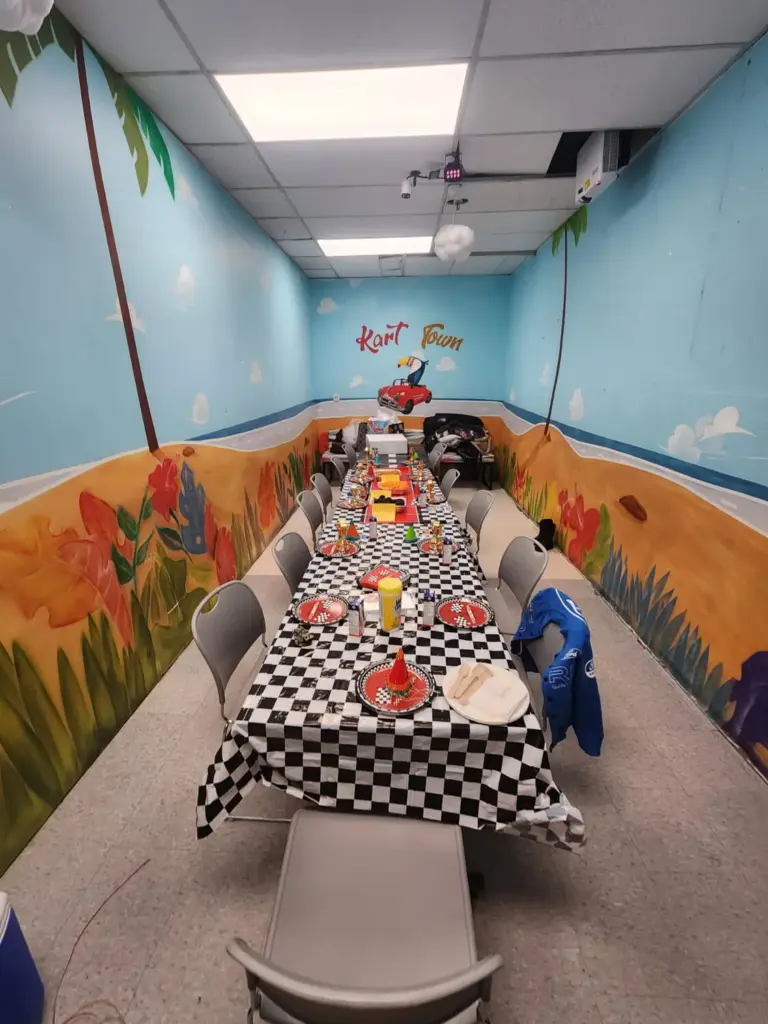 Bird Room birthday party space with blue sky, flowers and a toucan driving a car mural at Kart Town