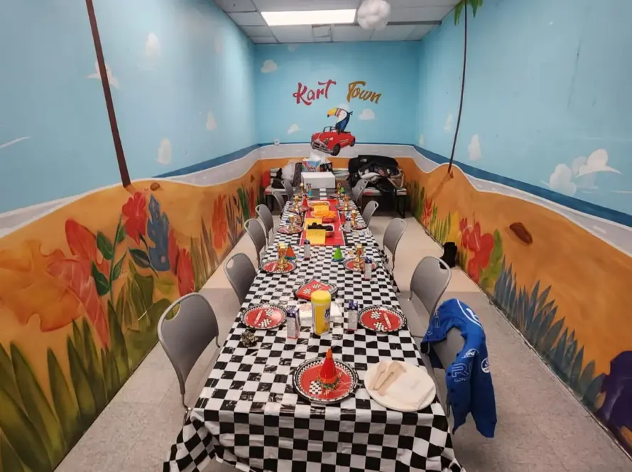 Bird Room birthday party space with blue sky, flowers and a toucan driving a car mural at Kart Town