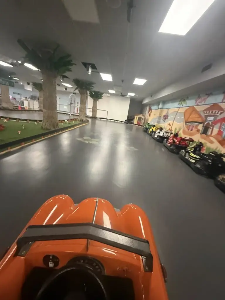 Bright driver point-of-view of the indoor go-kart track straightaway at Kart Town