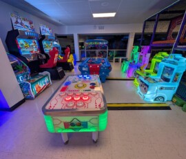 Explore a bright, jam-packed arcade floor with games for every age. Wide view of the brightly lit arcade floor full of games at Kart Town Aurora