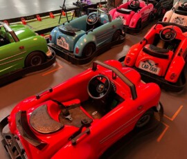 The full Kart Town classic car fleet — green, blue, red, pink and white — lined up and ready to race. Fleet of pastel classic ride-on cars in green, blue, red, pink and white parked on grid