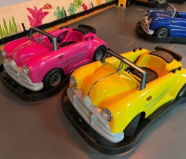 Vibrant pink and yellow retro cars ready to cruise — every ride feels like a special occasion. Pink and yellow classic ride-on cars parked ready for kids to drive