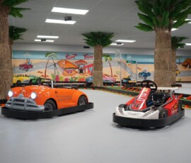 Pick your colour and hit the palm-lined track. Orange and red go-karts parked on the indoor track among the palm trees
