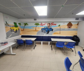 Our Monkey Room features a playful beach mural — a bright, private space for birthday celebrations. Monkey Room birthday party space with palm tree beach mural and monkey driving a car at Kart Town Aurora