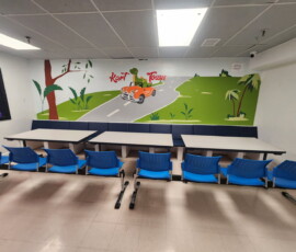 Celebrate in our Dino Room — a bright dinosaur-themed party space with its own seating and table. Dino-themed birthday party room with green hills and dinosaur car mural at Kart Town Aurora
