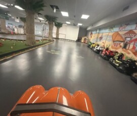 Take the wheel — here's the bright view from the driver's seat down the straightaway. Bright driver point-of-view of the indoor go-kart track straightaway at Kart Town Aurora